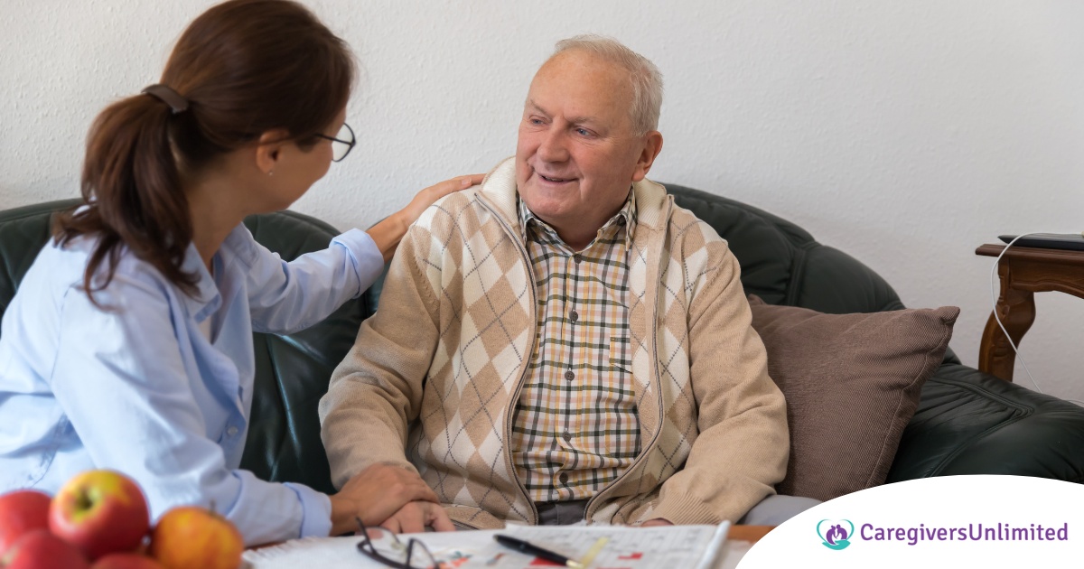 A caregiver compassionately listens to an older man, representing the kind of patience and empathy that help with communicating with clients who have dementia.