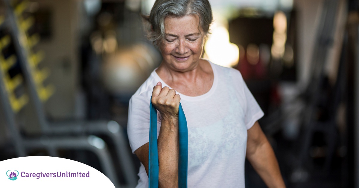 An older woman uses a resistance band to exercise, representing how staying active can help older adults keep their blood pressure in a healthy range.