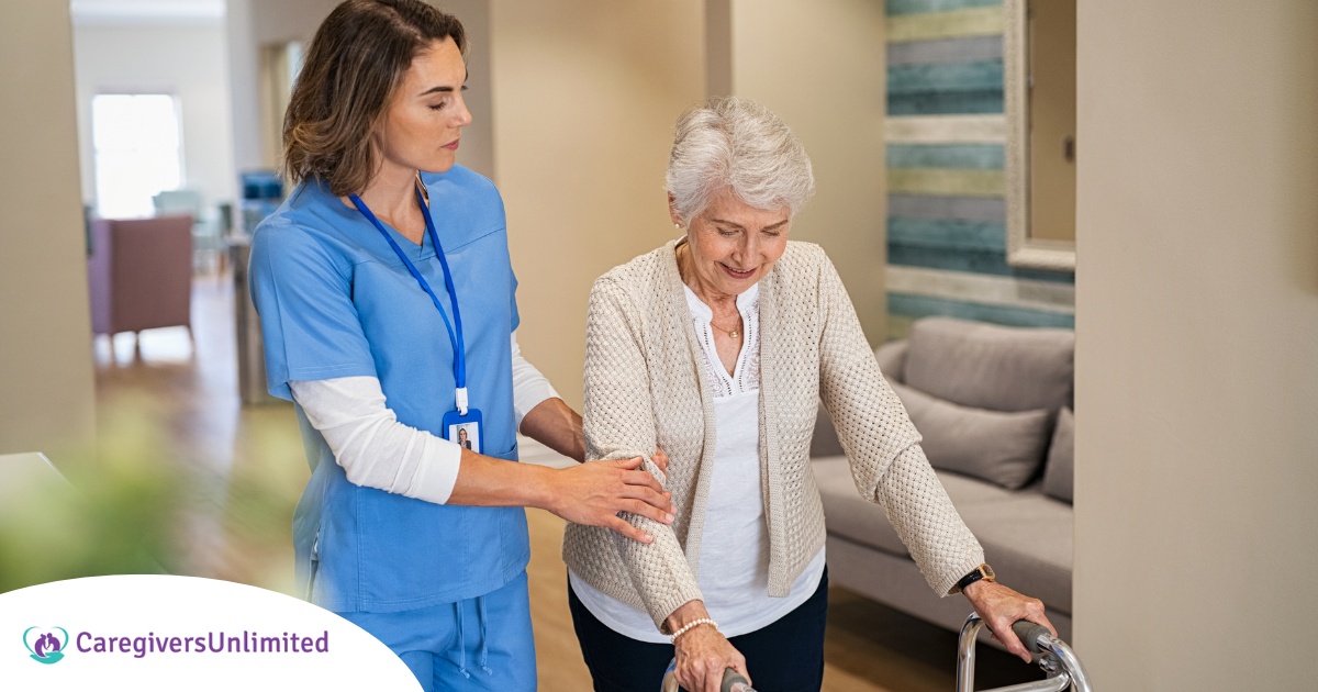 A professional caregiver helps an older client with a walker get around.