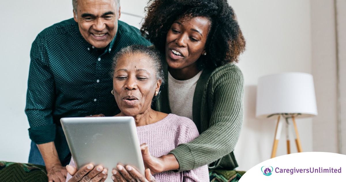 A daughter looks at a tablet with her older parents, representing technology and how ti can help with aging in place.