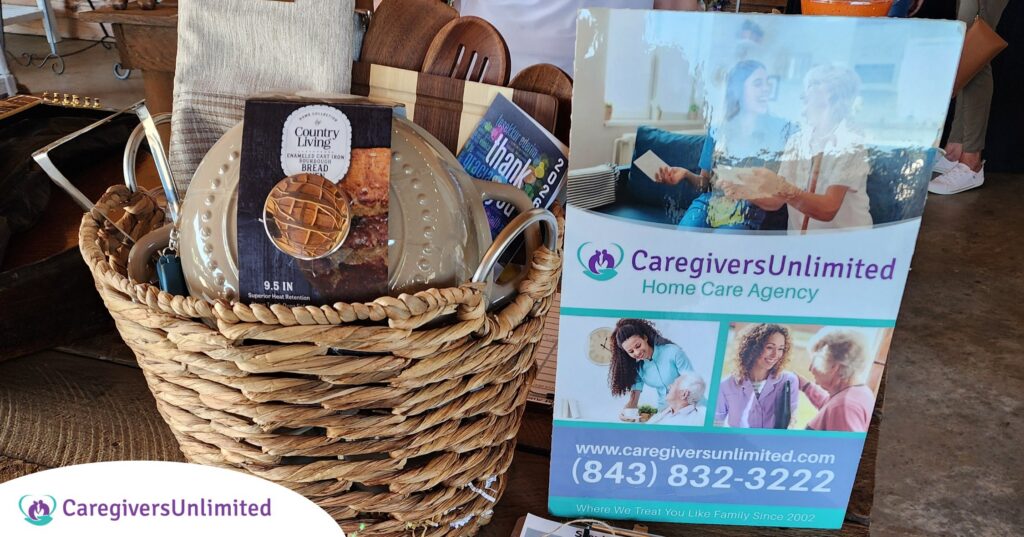 A large woven raffle basket filled with Country Living sourdough bread-making supplies is displayed next to a Caregivers Unlimited marketing sign at the PAWS 2026 fundraising event.