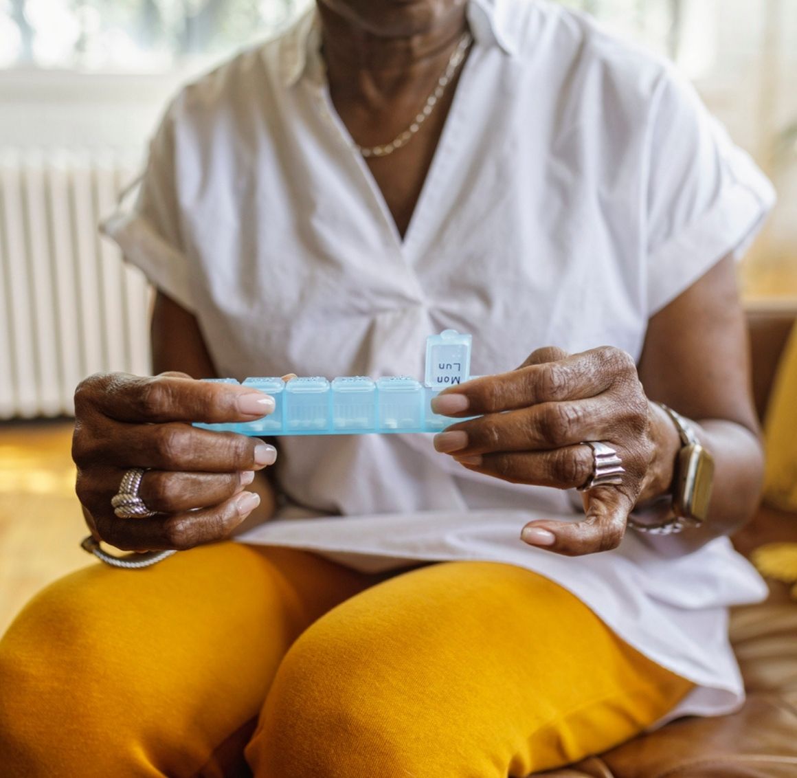 Senior woman organizing medications in a pill organizer for Medication Supervision in Charleston.